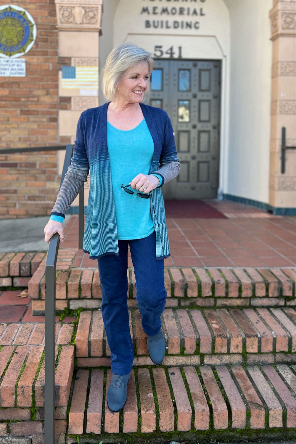 over 50 blogger jennifer connolly walking down stairs in turquoise sweater from nordstrom