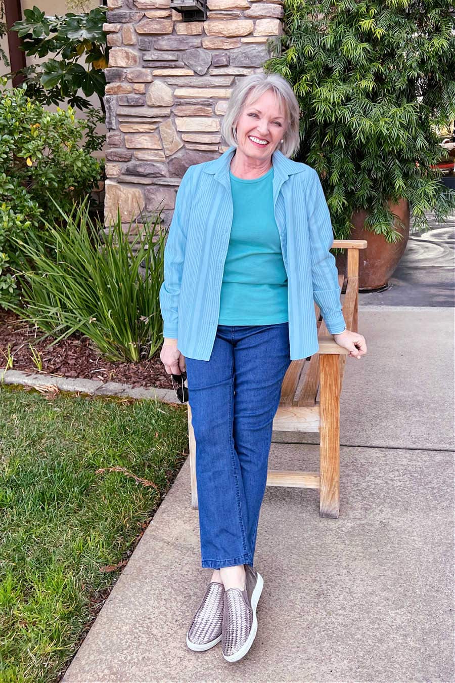woman leaning on bench wearing blue jeans and striped shirt