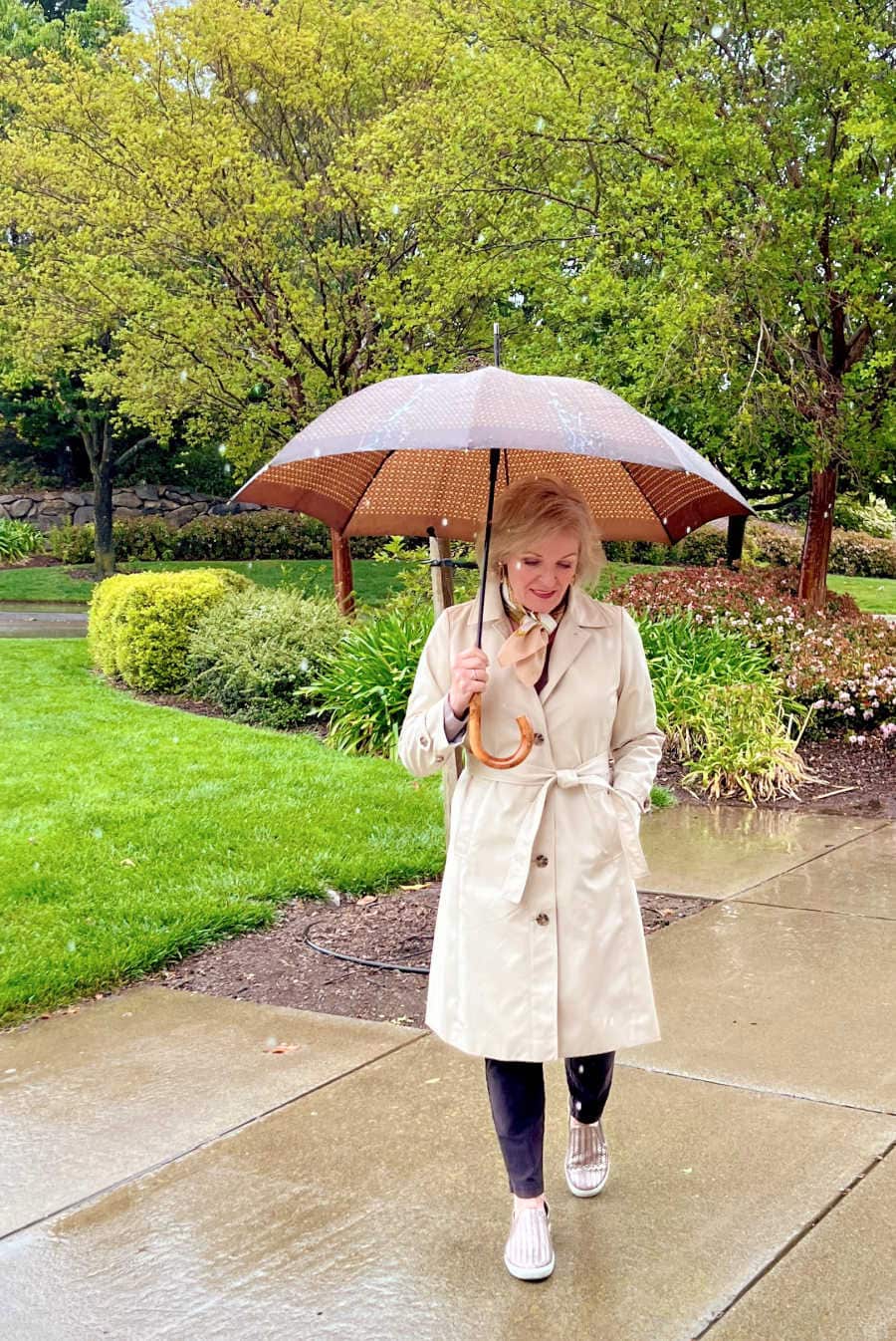 WOMAN WALKING IN RAIN WEARING CLASSIC SPRING TRENCH COAT