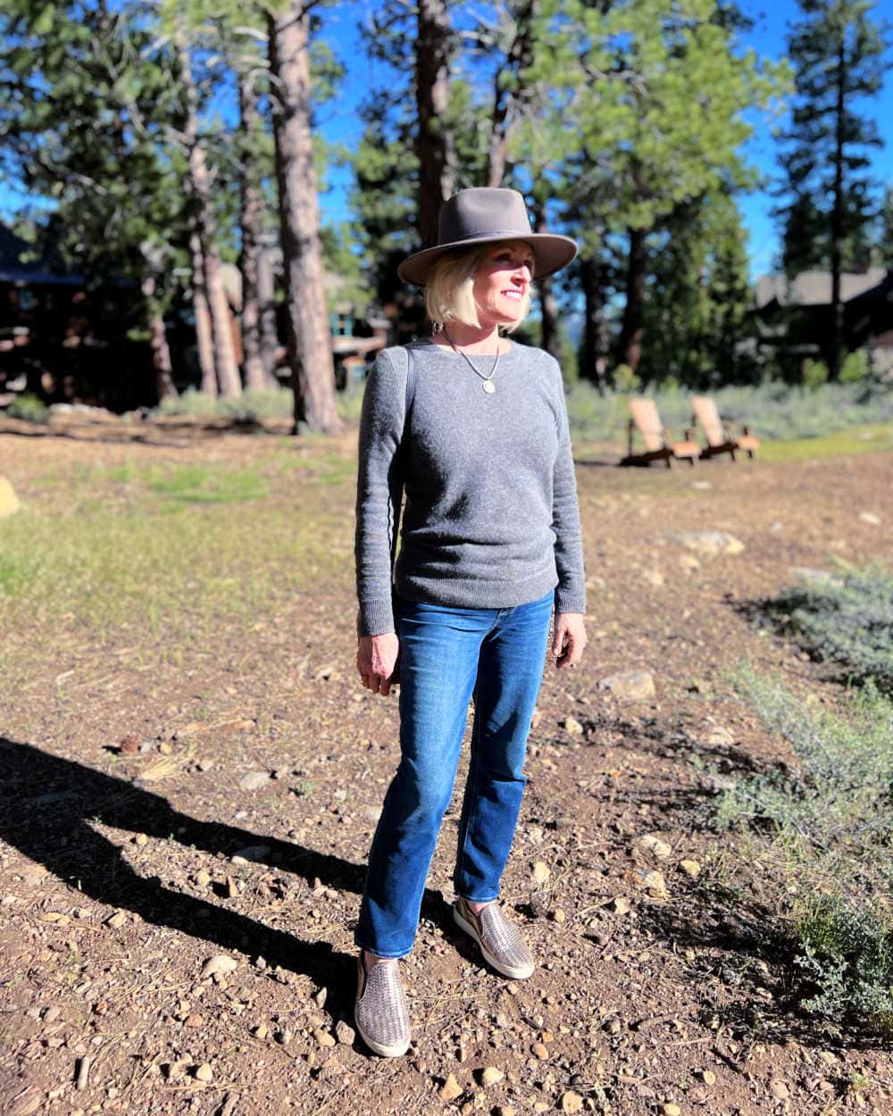 woman wearing cashmere sweater and grey fedora in forest