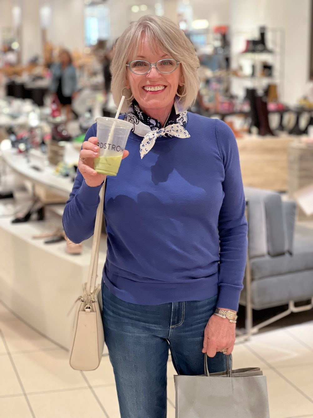 woman wearing blue sweater and sc arf drinking matcha tea