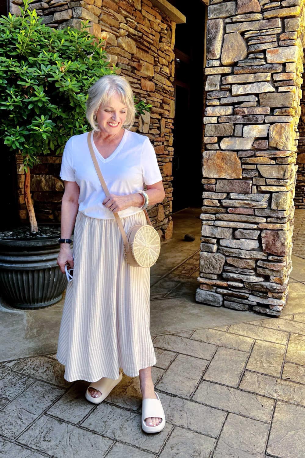 woman wear striped skirt with white tee and round straw bagan