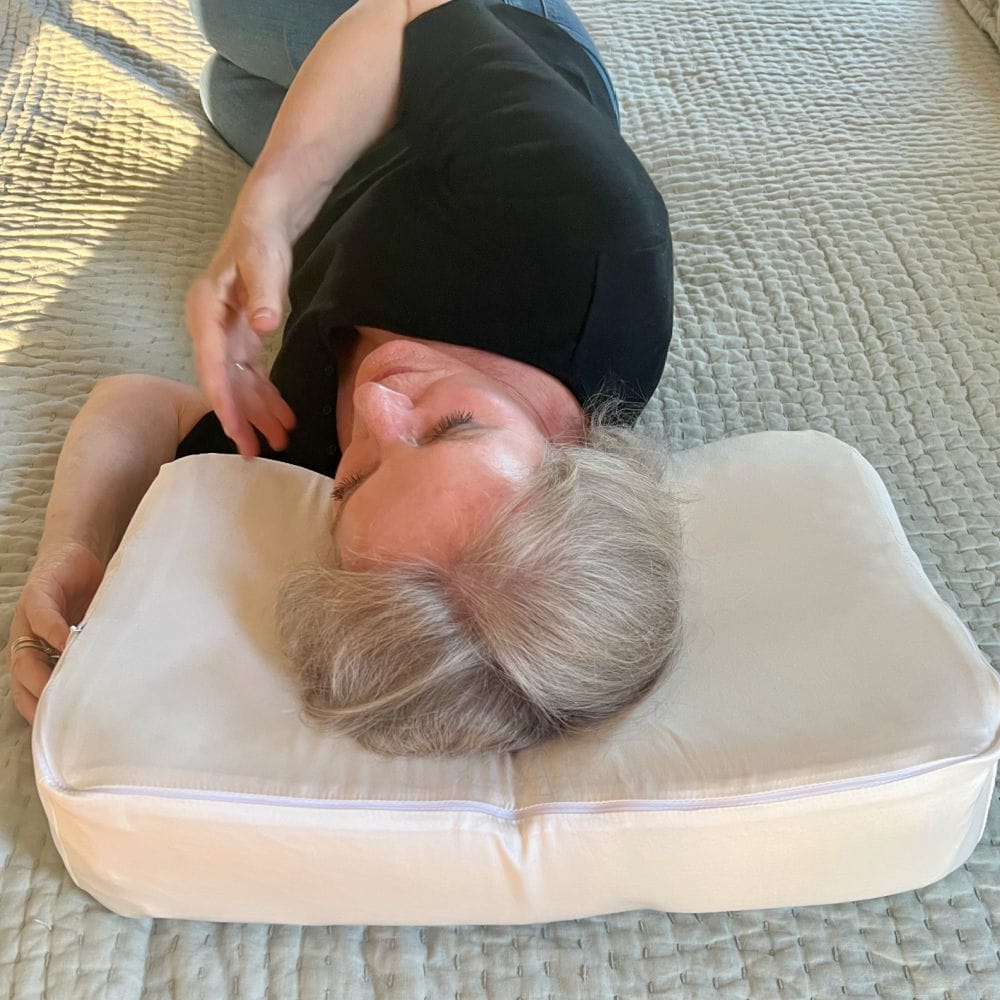 silver hair senior woman laying on ergonomic Envy pillow to improve her posture