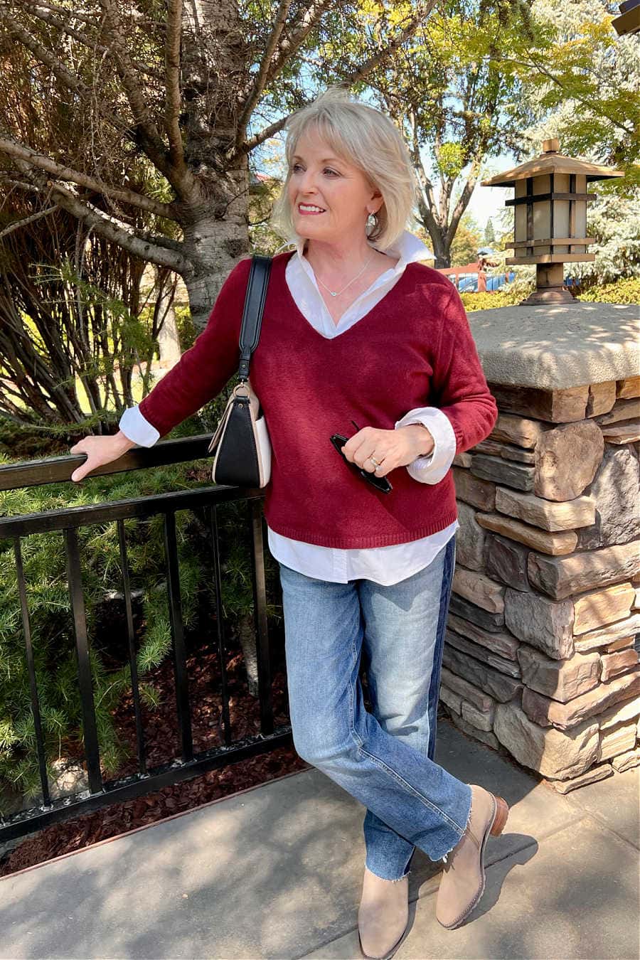 woman wearing burgindy sweater over white shirt and jeans