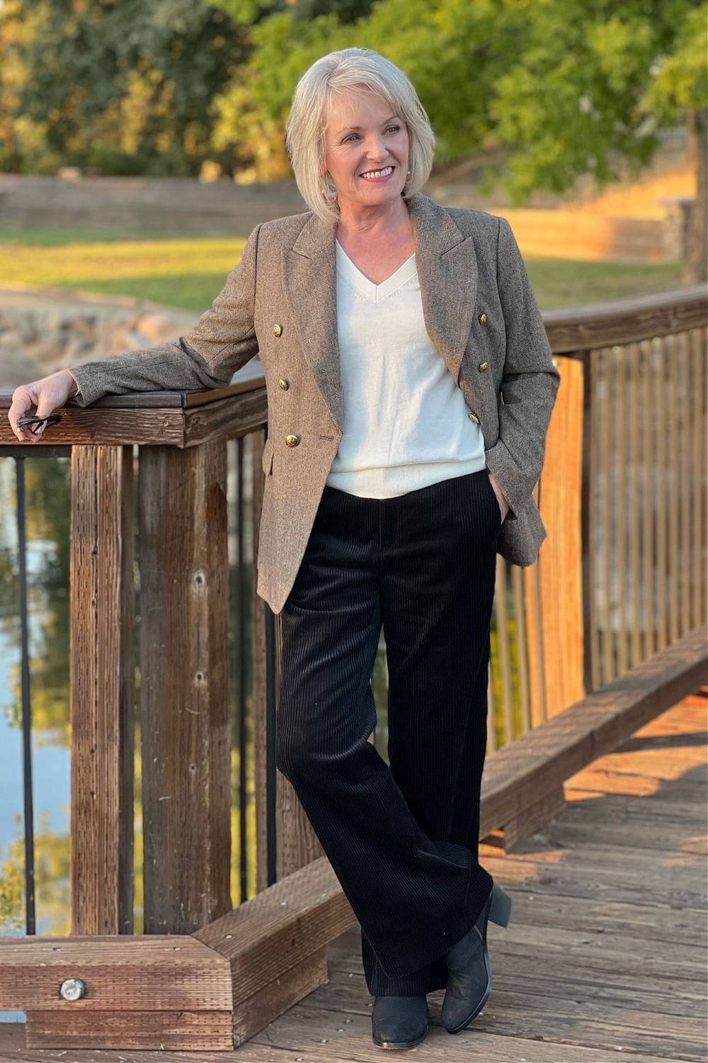 WOMAN LEANING ON FENCH WEARING BLAZER AND BLACK PANTS