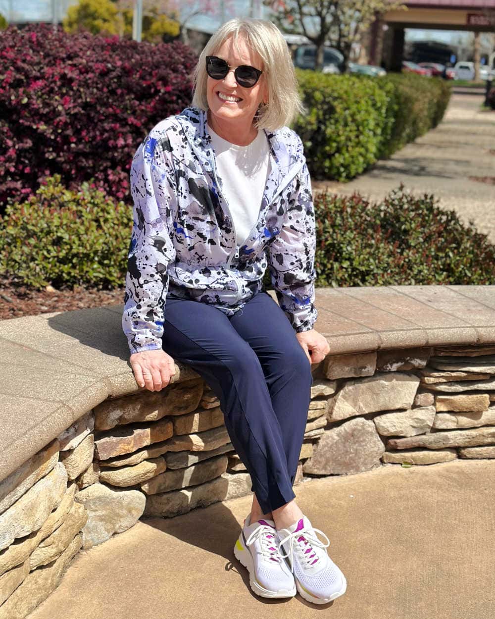 WOMAN SITTING ON WALL WEARING EASY SPIRIT DENISE AUSTIN MEL EMOVE WALKING SNEAKERS