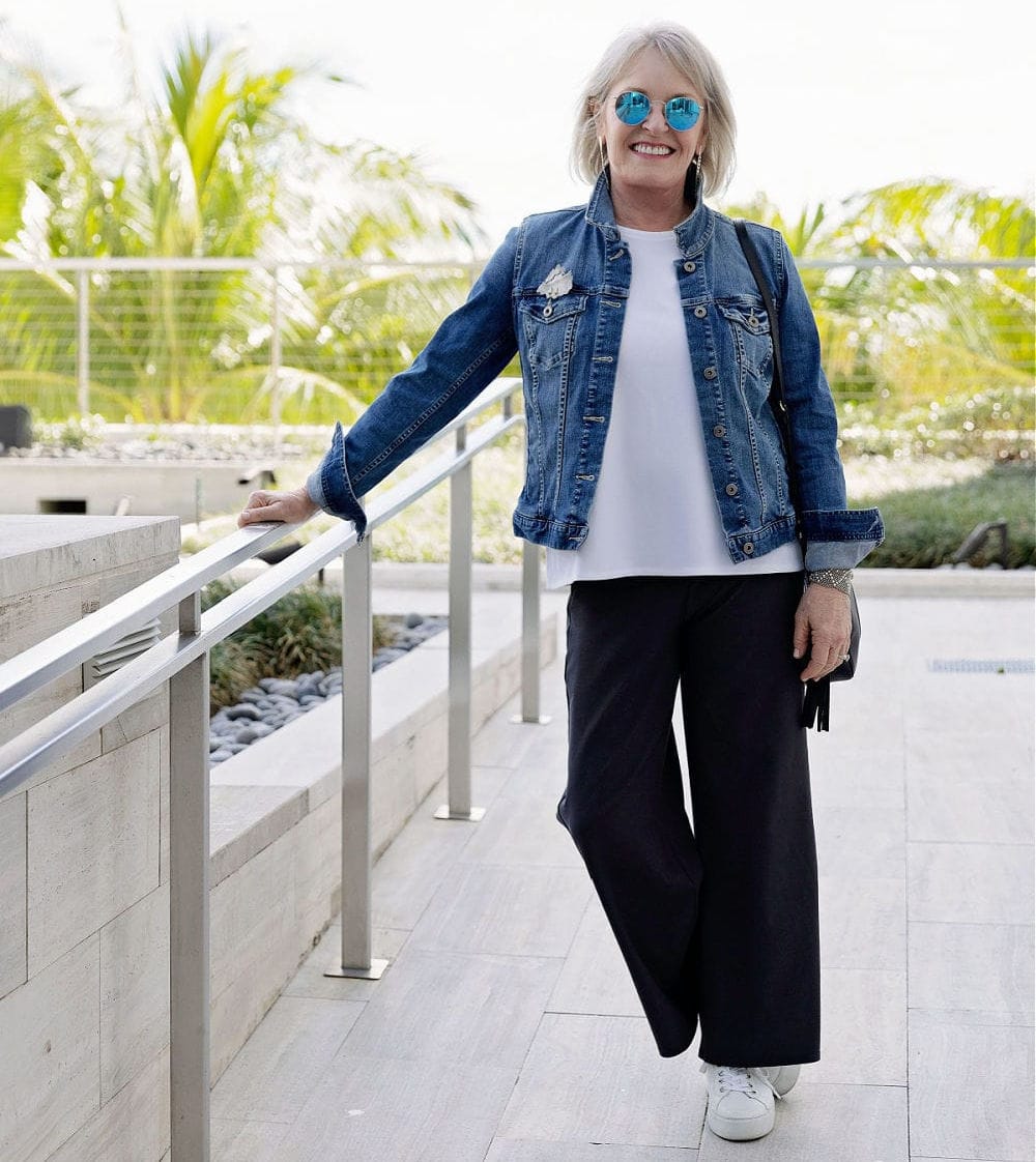older lady wearing denim jacket over black cropped pants with white sneakers