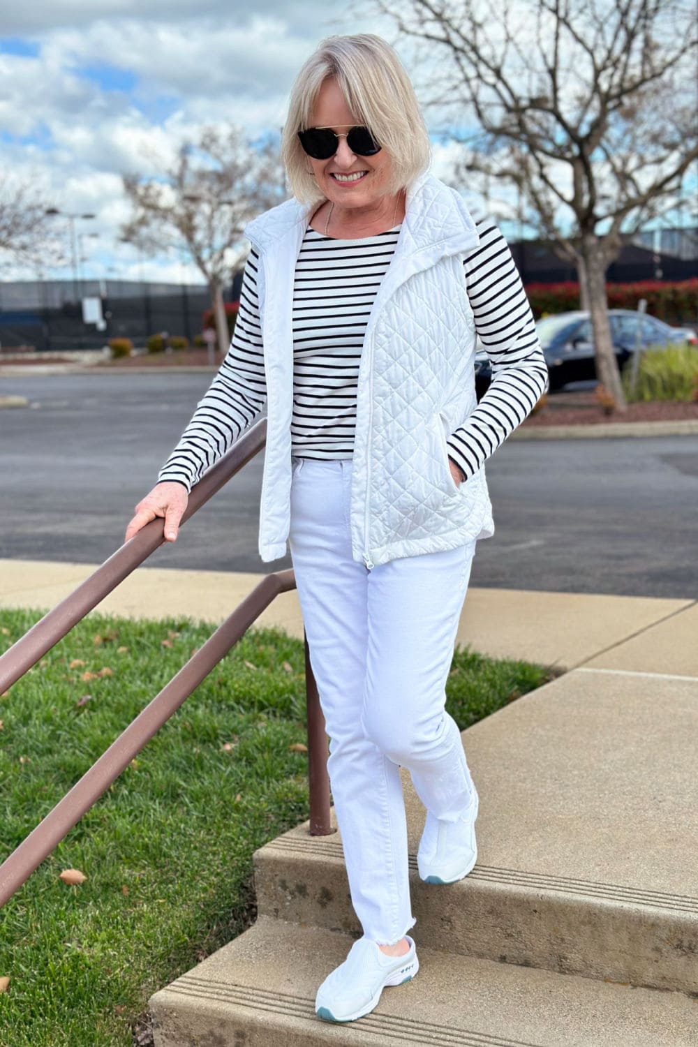 woman walking down steps in easy spirit traveltime clogs and white jeans