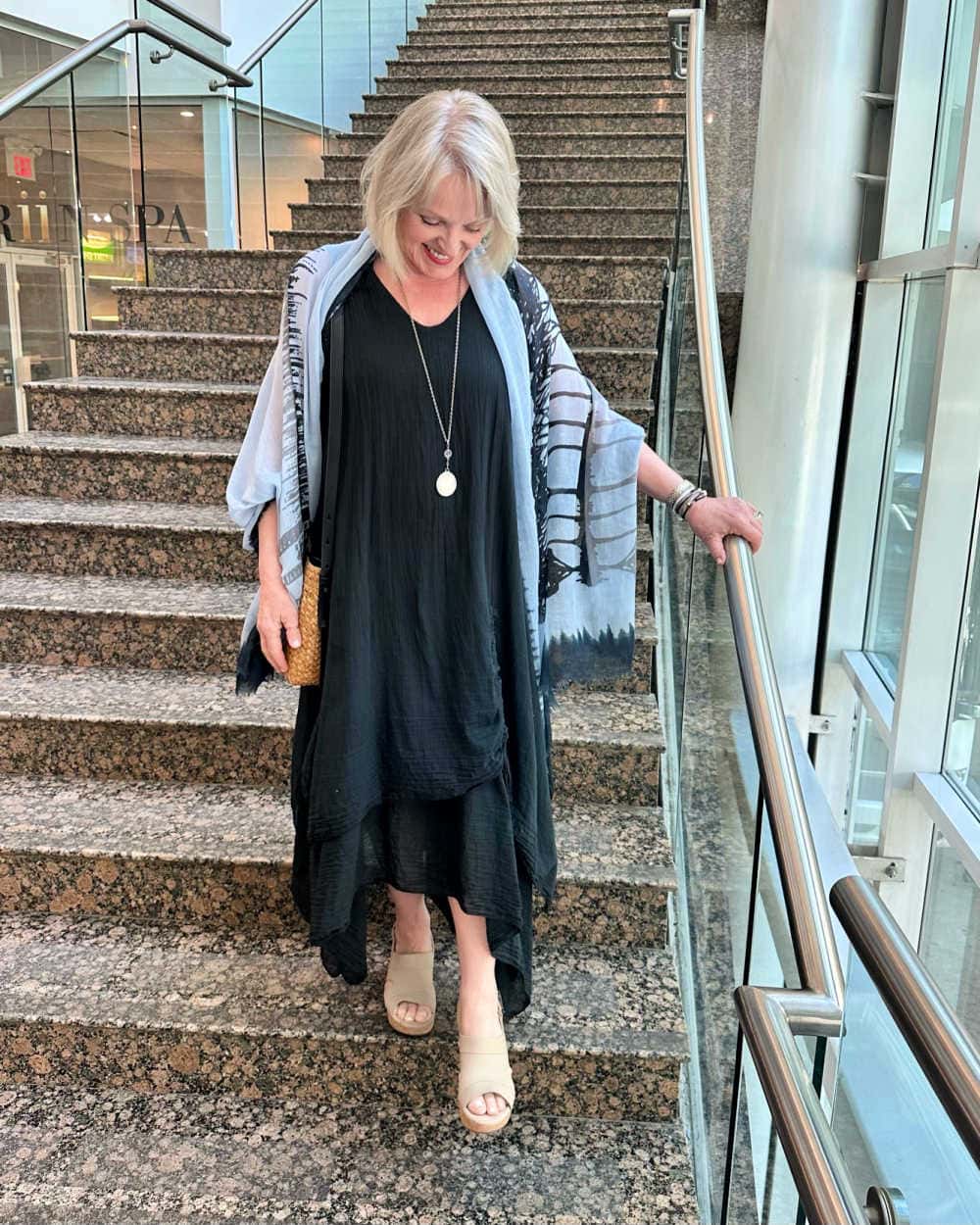 woman wearing lightweight black summer gauze dress and colorful scarf on staircase