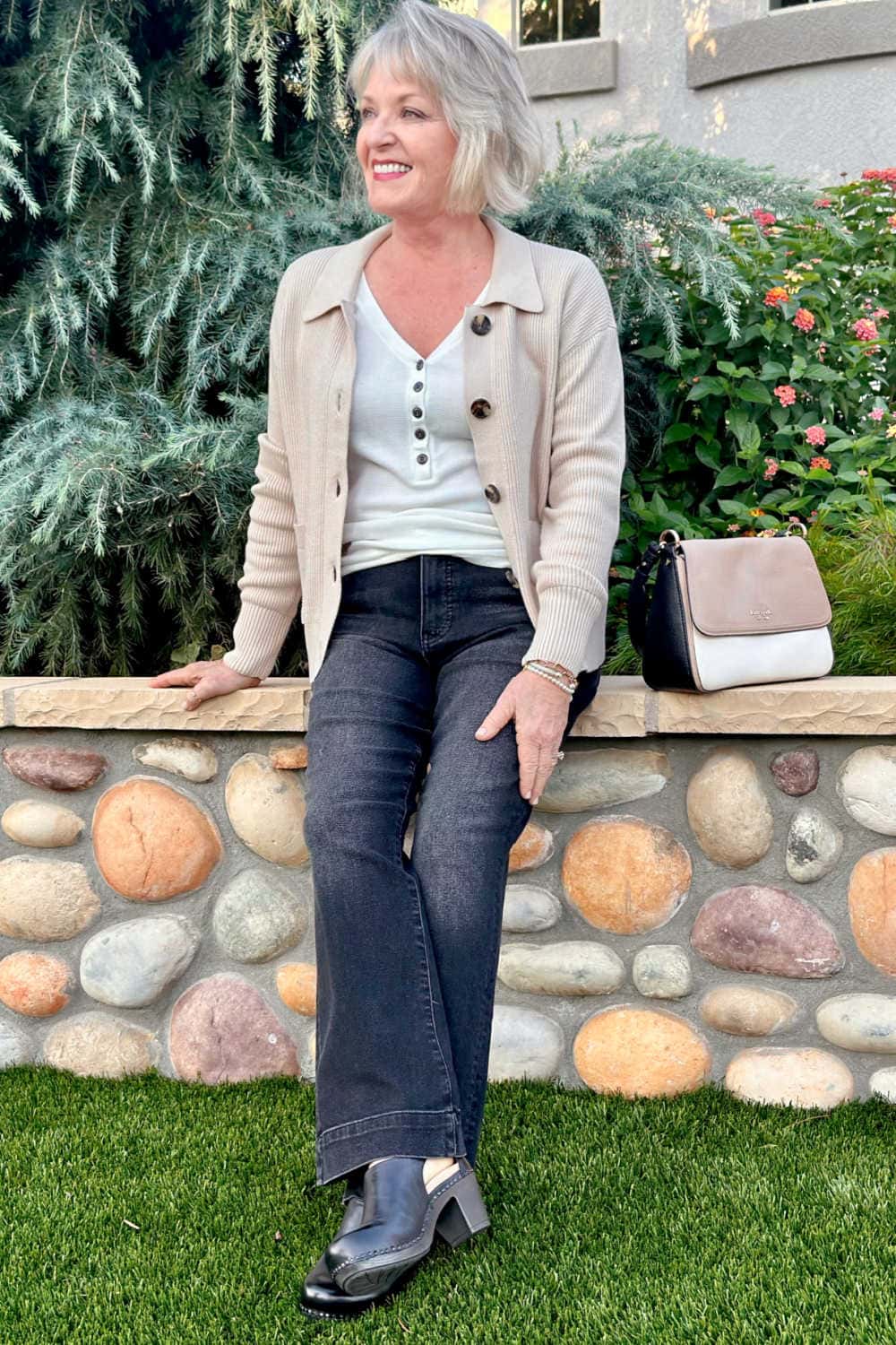 woman wearing clogs shoe trend for fall with jeans and beige sweater