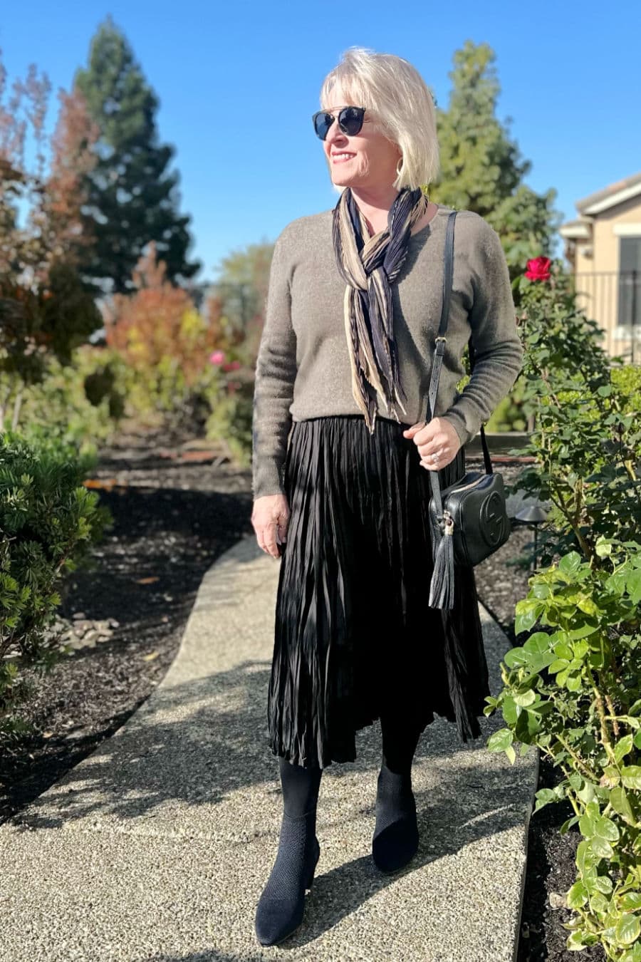 Over 50 woman showing how to wear ankle boots with a skirt
