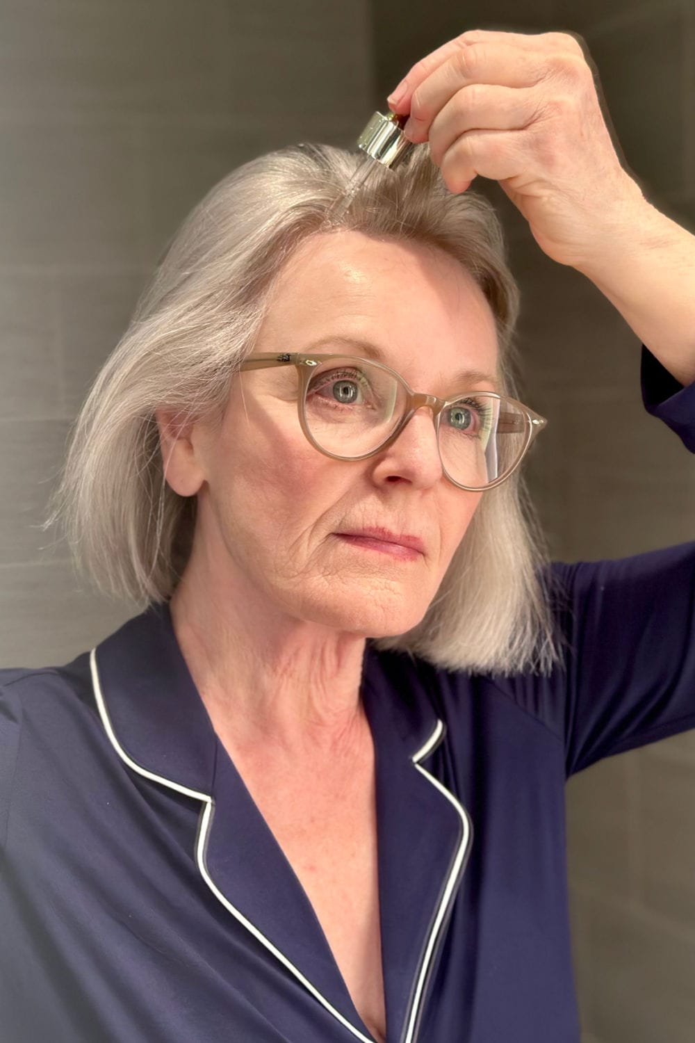mature, silver hair woman using hair serum for her thin hair