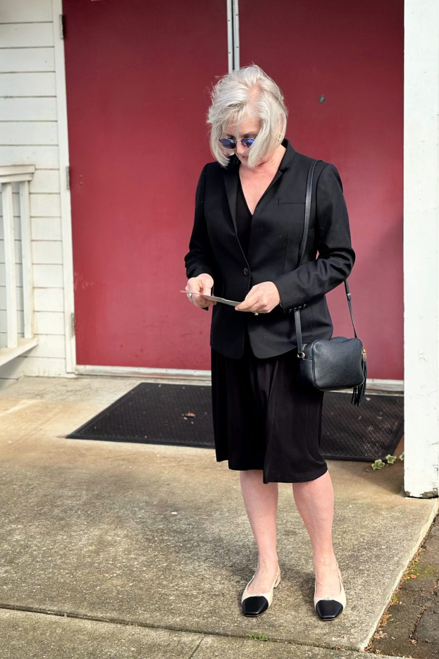 Stylish older woman in black blazer and midi skirt dressed for a funeral