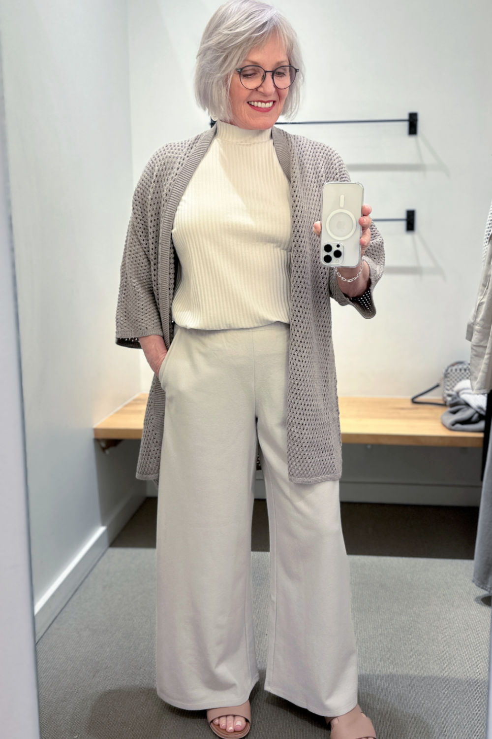 woman trying on eileen fisher regenerative wool cardigan with boiled wool trousers