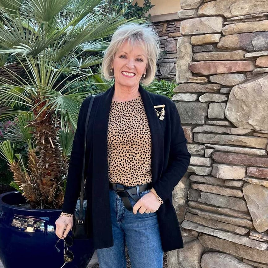 older woman wearing leopard sweater trend with black blazer and blue jeans