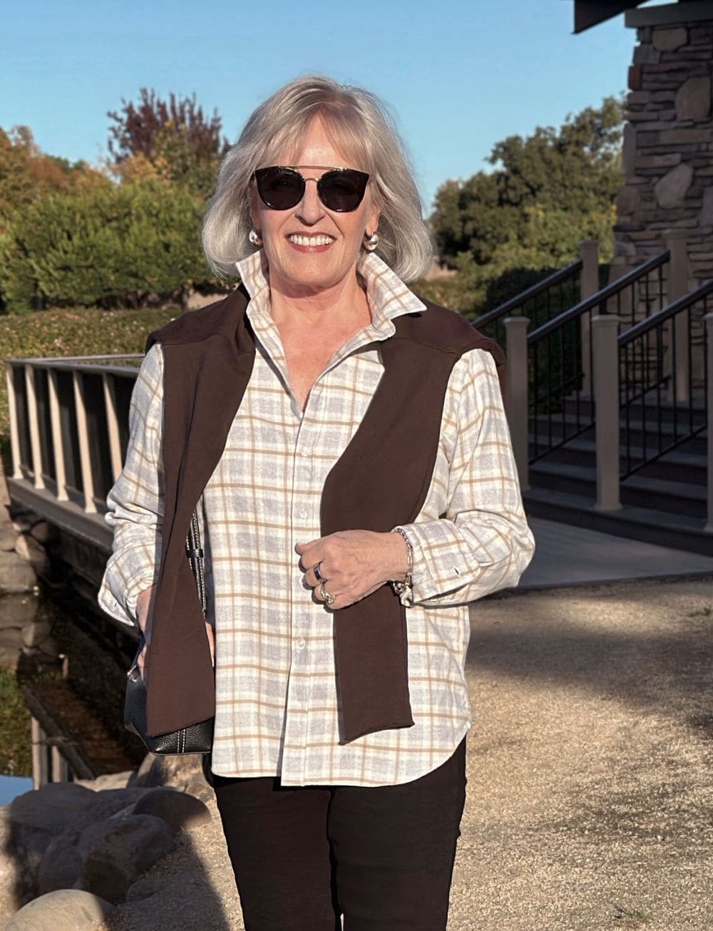 woman wearing plaid flannel shirt with brown sweatshirt over shoulders