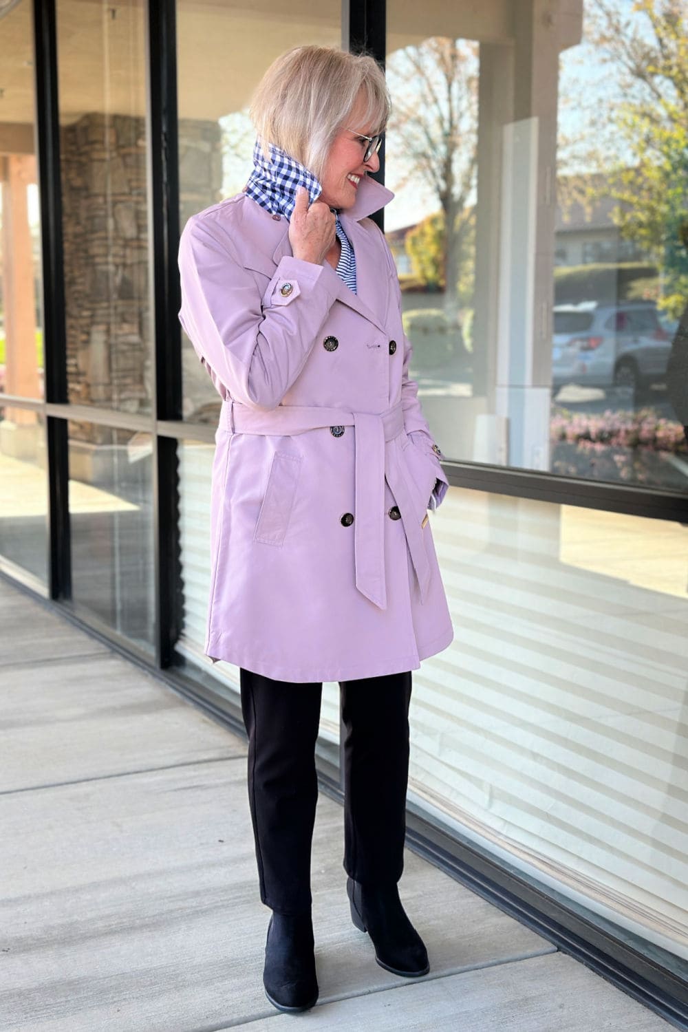 Stylish mature woman in a pastel trench coat with gingham collar detail, perfect for cool spring days.