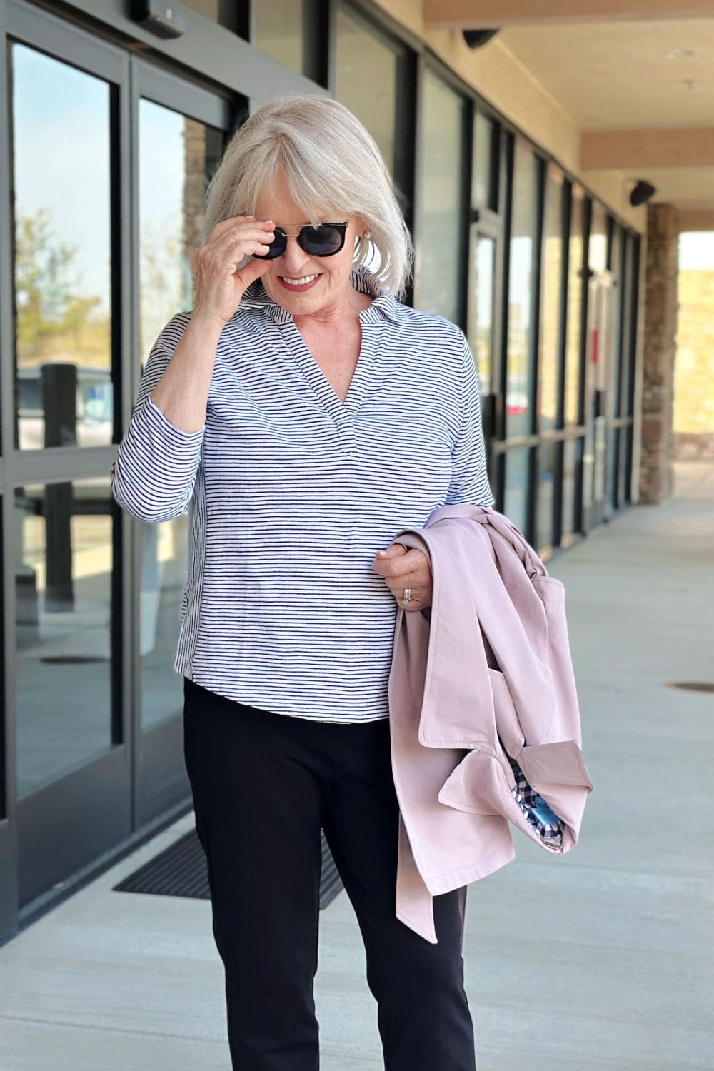 Casual spring outfit with a white slub cotton polo and ponte pants on a woman over 50.