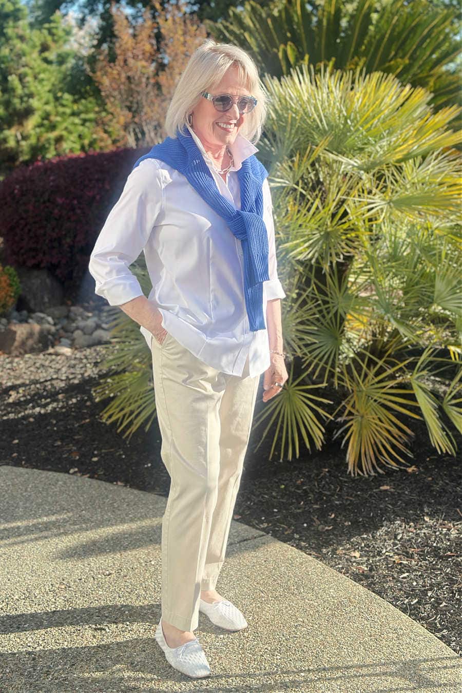 Casual outfit idea with white shirt,. chinos, sweater over shoulders and flats for women over 60 to look polished in under 10 minutes