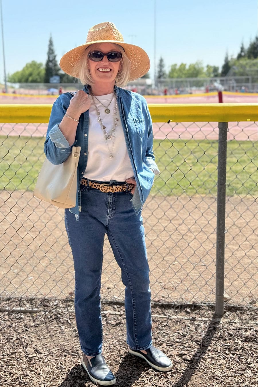 woman wearing double denim outfit with slip on sneakers and big sunhat