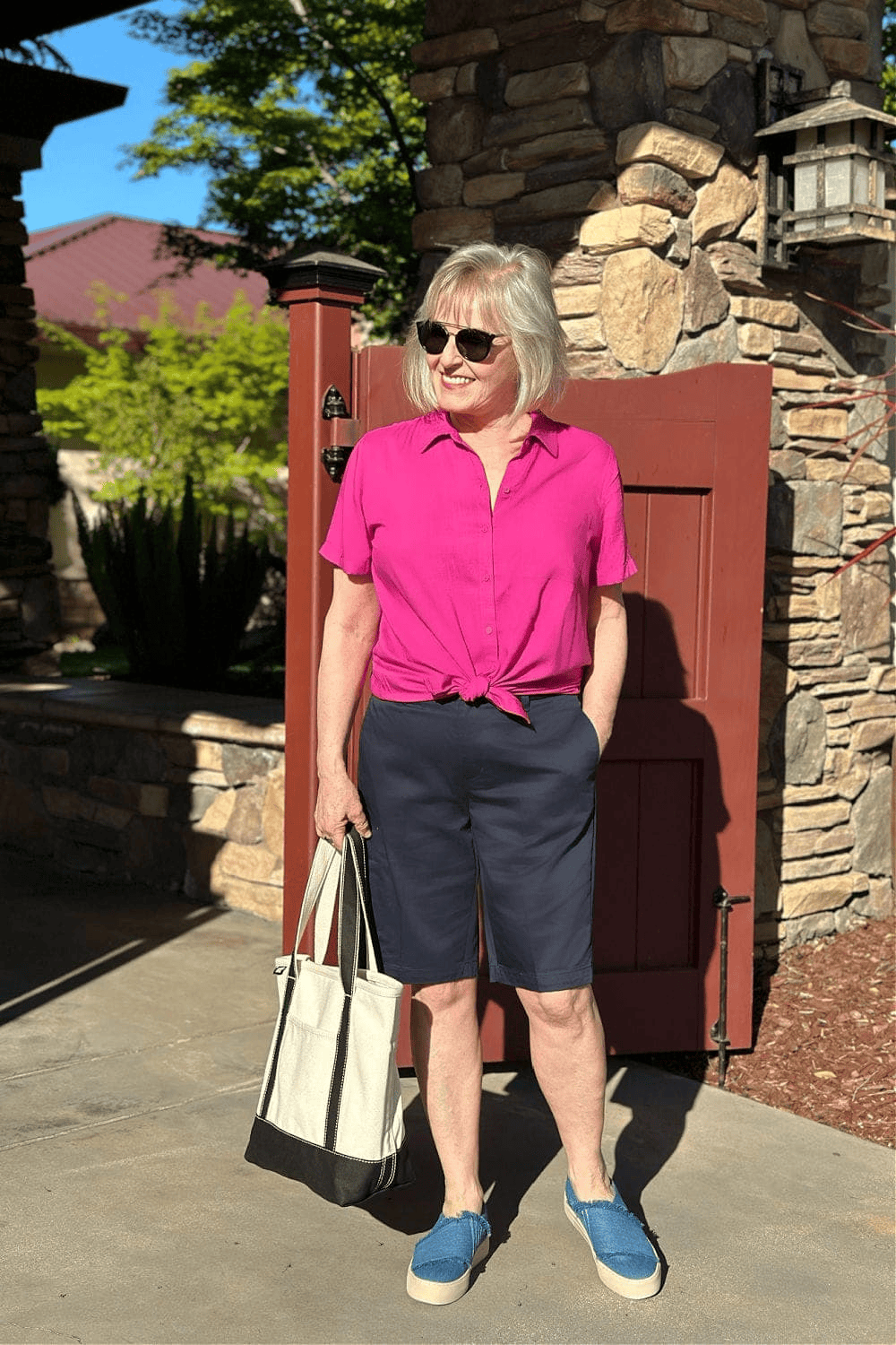 woman over 60 wearing navy chino shorts and pink shirt