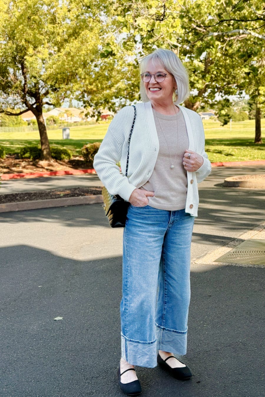 Comfortable and relaxed outfit for women over 60 with wide-cuffed denim, oatmeal sweater, and white cardigan