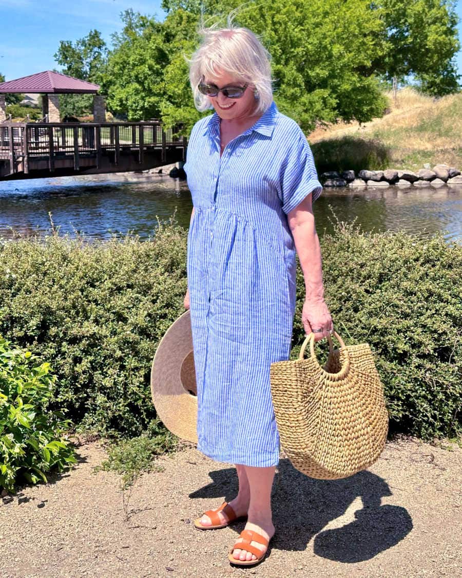 Woman over 60 wearing Talbots striped shirtdress with sandals and straw tote, stylish summer outfit idea