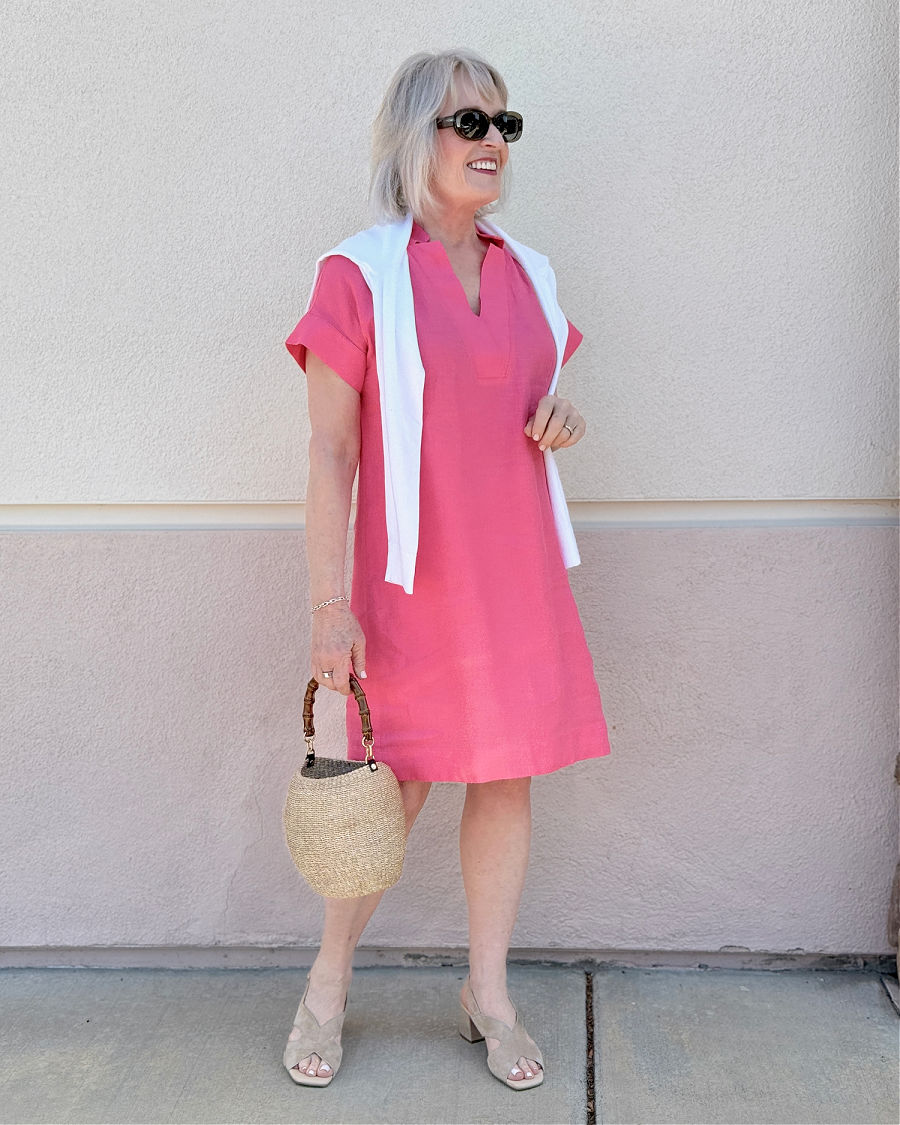 mature woman wearing Talbots Camellia Rose linen shift with cardigan around shoulders and straw bag