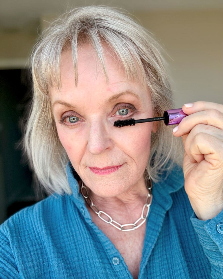 woman over 60 applying best drugstore brand Elf mascara on mature eyes