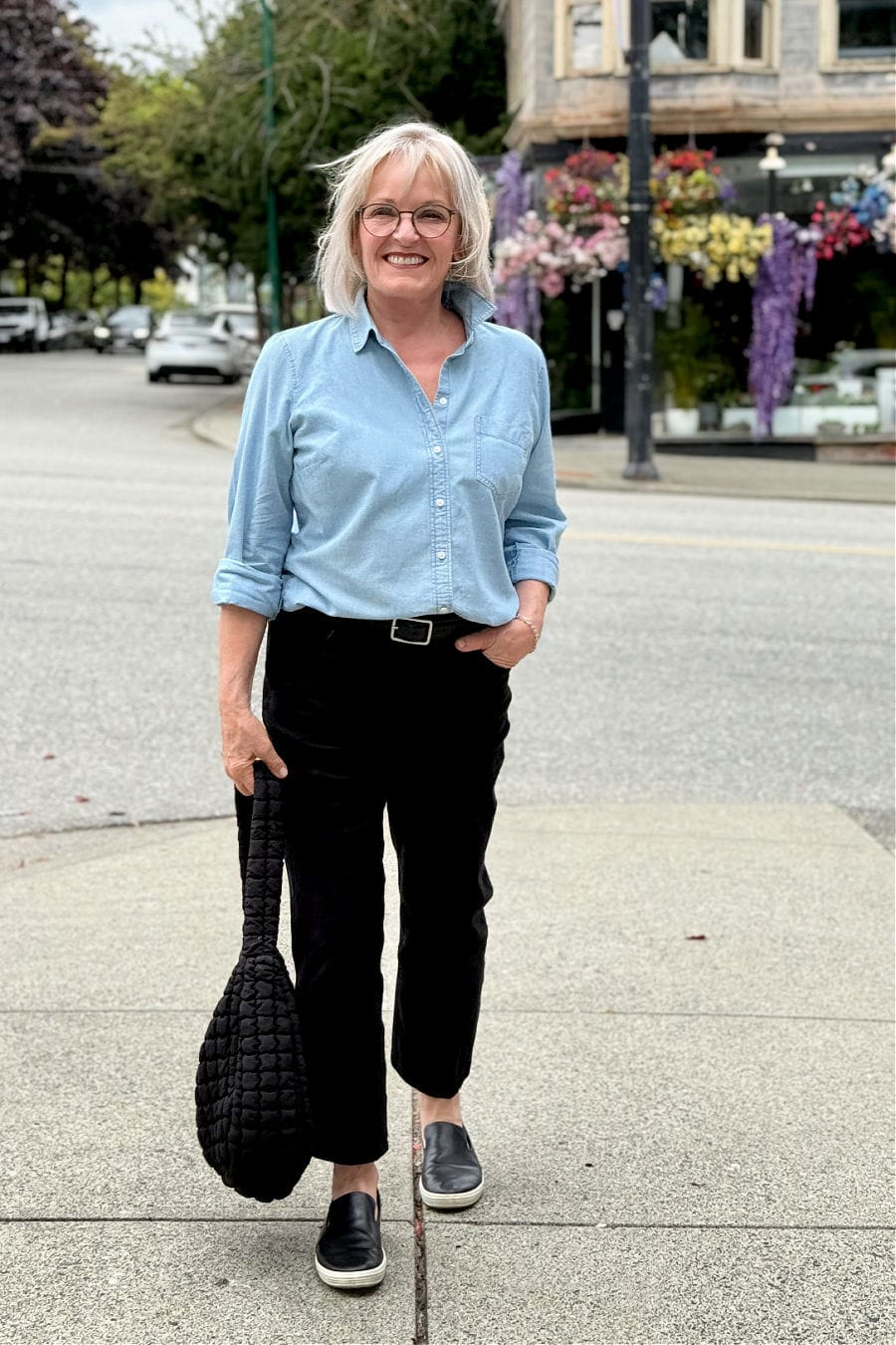 Polished everyday style for women over 60 in chambray shirt, black jeans, and slip-on sneakers