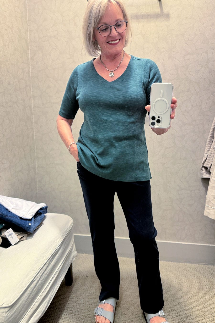 older woman wearing green tee and navy pants in J.jill dressing room try on