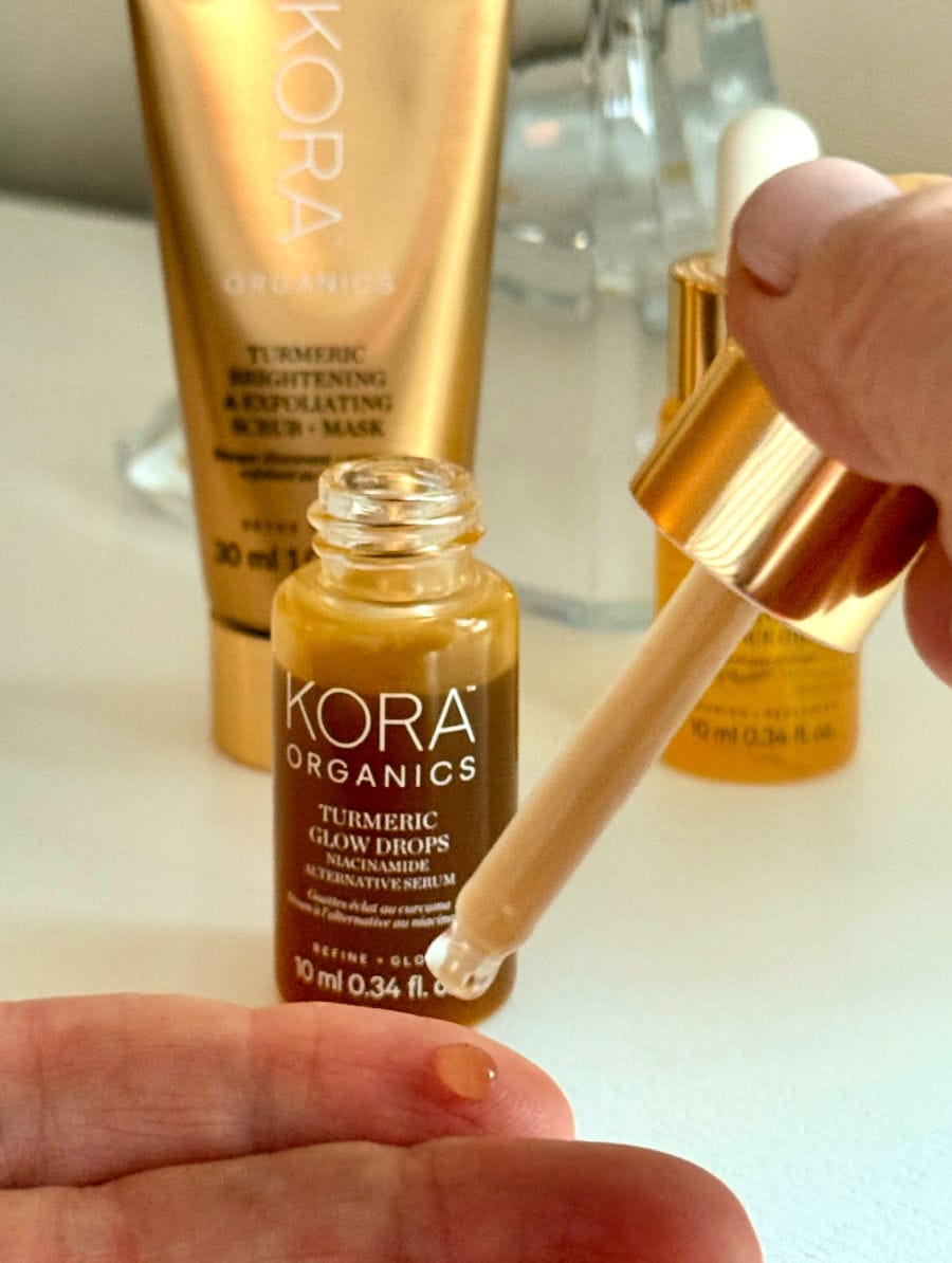 applying KORA Organics Turmeric Glow Drops from the dropper and bottle