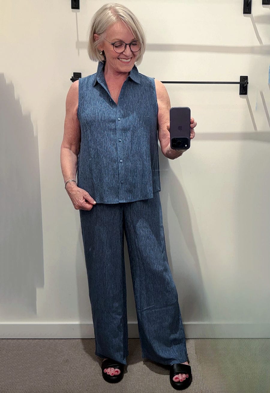 woman in eileen fisher dressing room trying on plissé sleeveless top and pants in blue