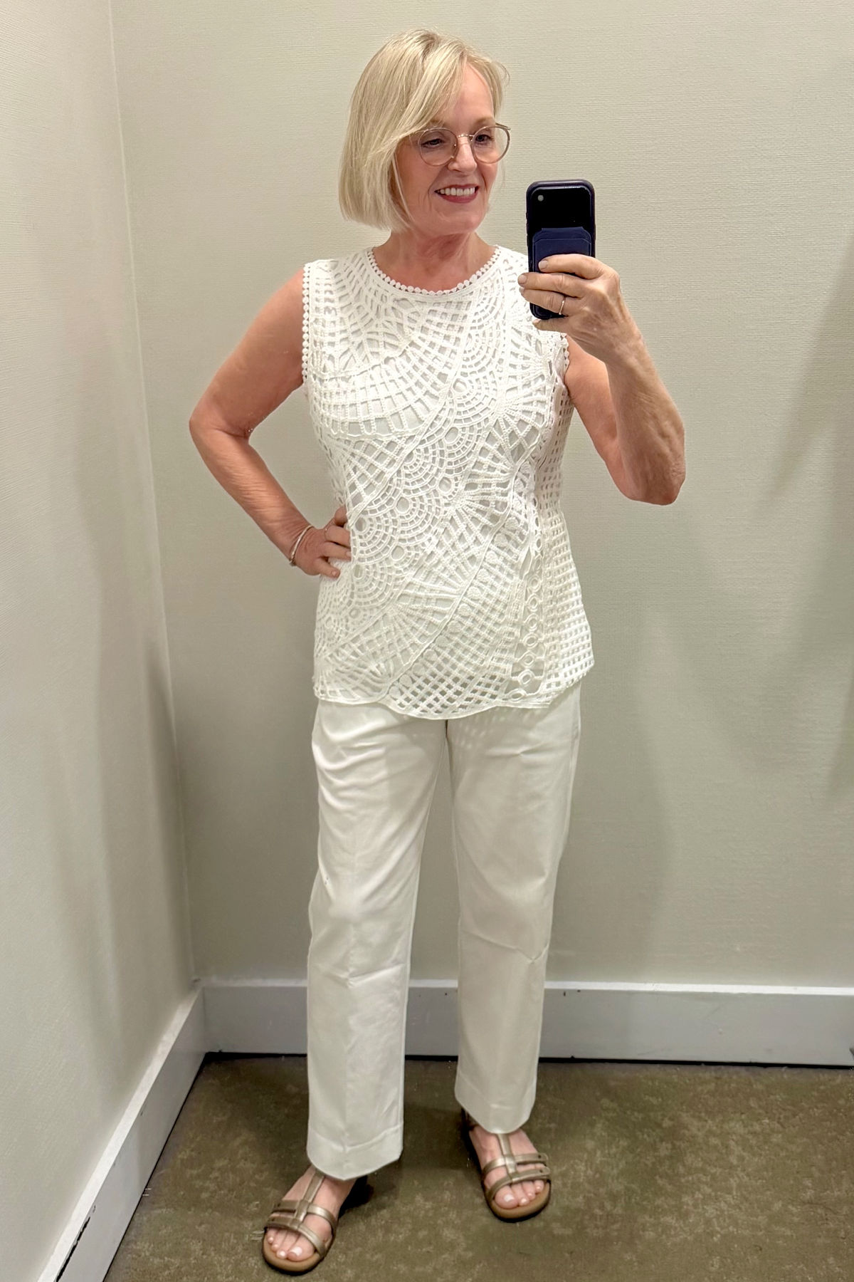 Jennifer Connolly wearing a white crochet sleeveless top with white cropped pants and metallic sandals from Chico's summer collection.